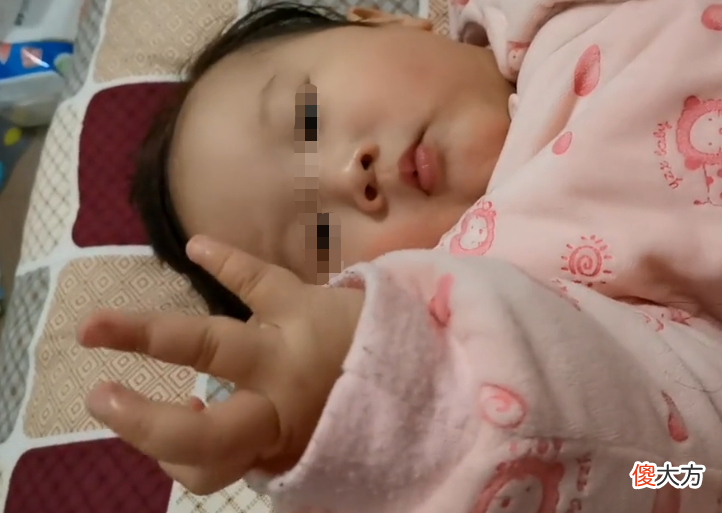 小婴儿专心“掰手指”，表情有些淡淡的忧伤，是在算挨训几次吗？